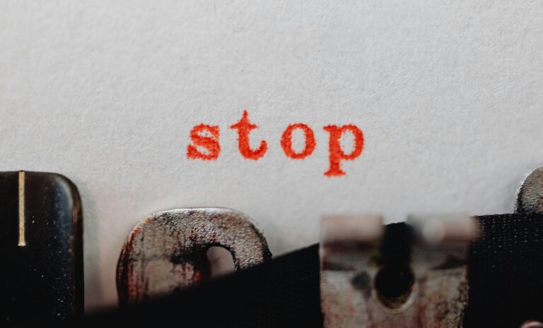 texto vermelho "stop" em uma folha branca. a folha está em uma máquina de escrever.